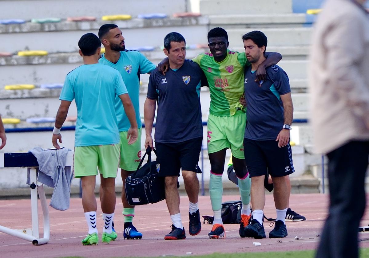 El jugador del Málaga, Moussa Diarra, asistido por el médico Pablo Campos y el fisioterapeuta Fernando Lacomba.