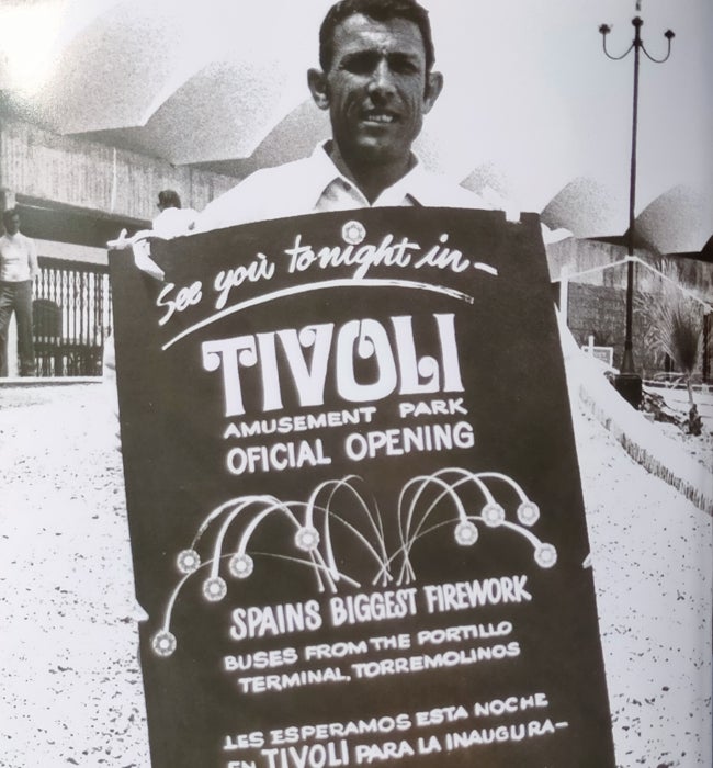 Un hombre sostiene un cartel anunciando el espectáculo inaugural con motivo de la apertura de Tivoli.