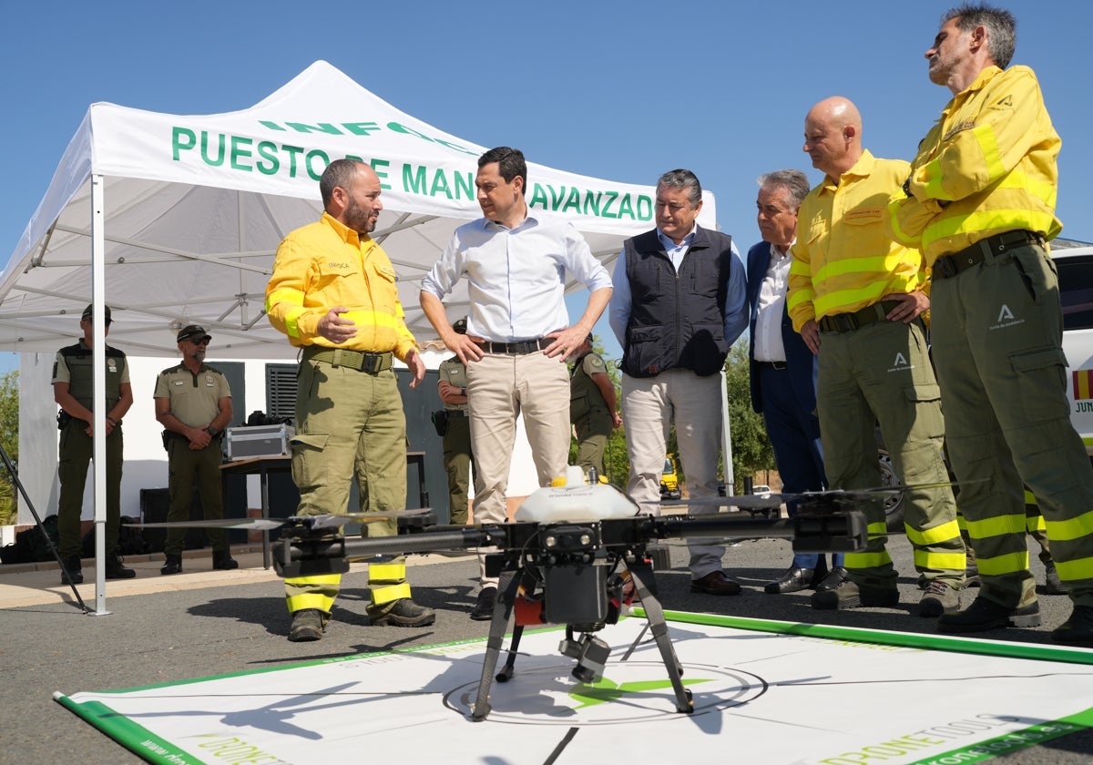 Juanma Moreno y el consejero Antonio Sanz observan junto a responsables del Infoca uno de los drones de vigilancia.