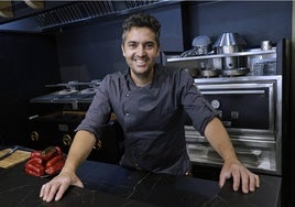 Juanjo Carmona, en la barra de Aviva, con la parrilla y el horno de brasa al fondo.