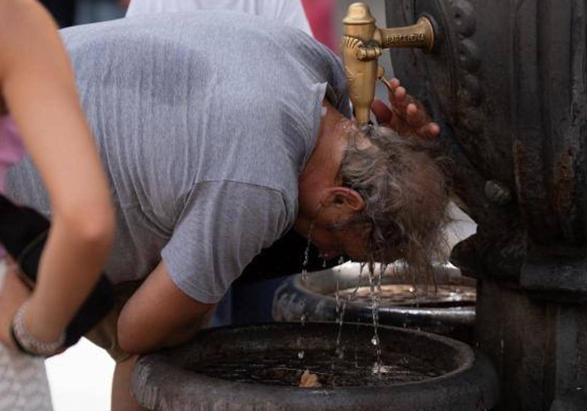 Un hombre se refresca en una fuente para combatir el calor.