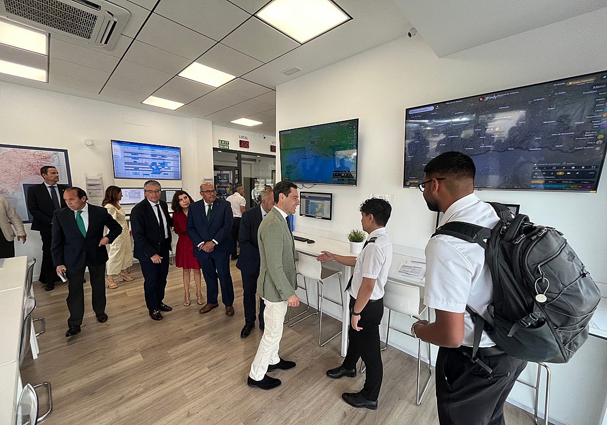 Imagen principal - Tres imágenes de la visita del presidente andaluz a la academia de pilotos de Vélez-Málaga.