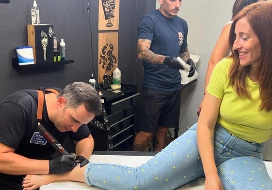 Uno de los trabajadores del estudio tatúa a una chica en la jornada solidaria.
