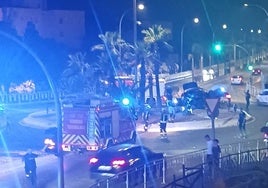 Un coche en la glorieta, policías locales, bomberos y vecinos, tras el último accidente en la rotonda de la Marcha Verde, entre los barrios de El Pinillo y Montemar Alto, en la antigua Nacional 340.