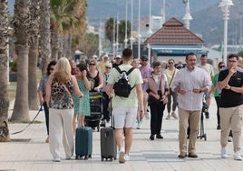 Turistas se desplazan hacia su alojamiento por el paseo marítimo de Málaga.