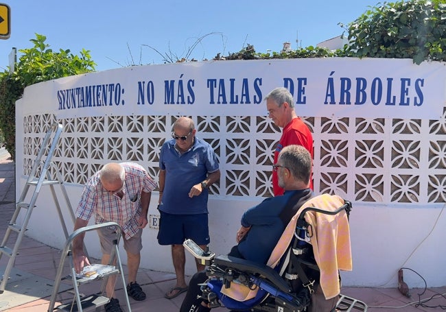 Vecinos de Guadalmar colocan una pancarta para protestar contra la tala de árboles en el barrio.