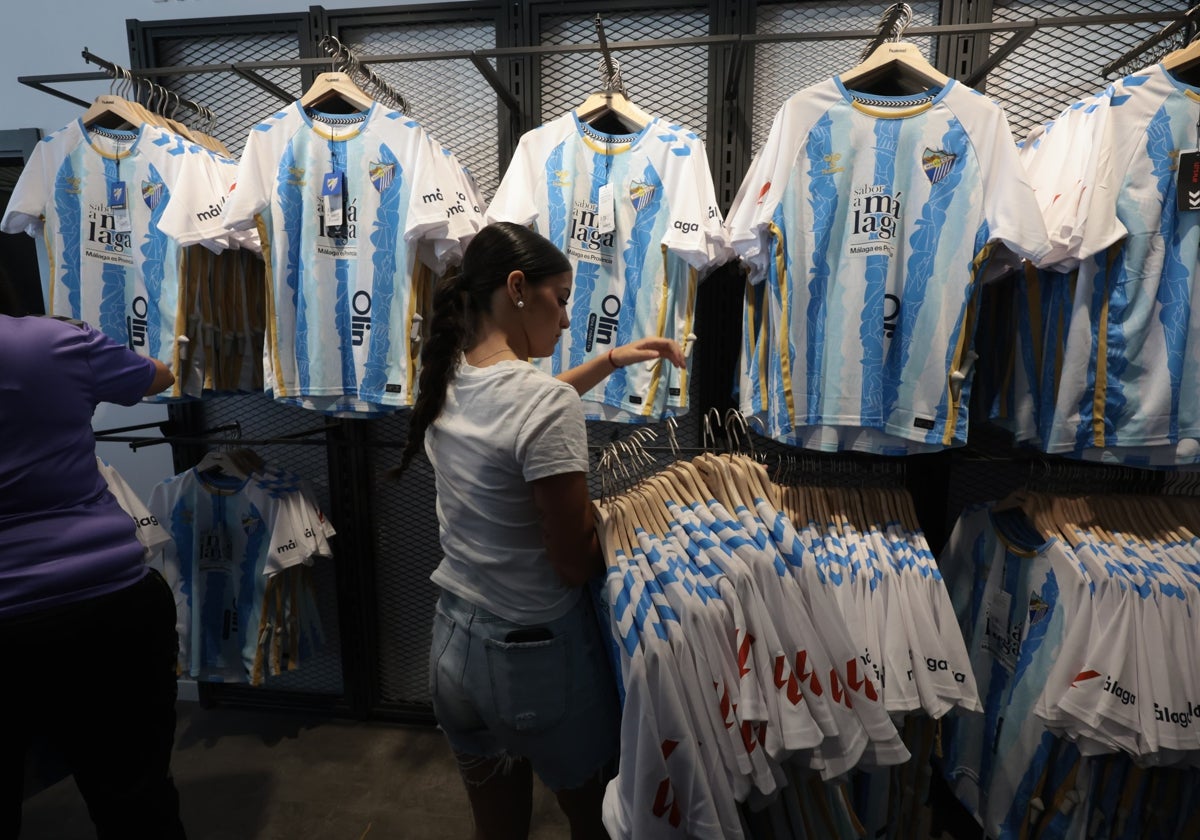 Una empleada de la tienda del Málaga repone una remesa de las nuevas camisetas.