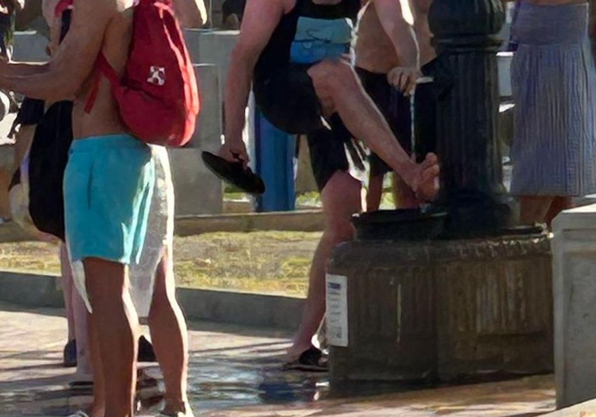 Bañistas se limpian la arena con la fuente.