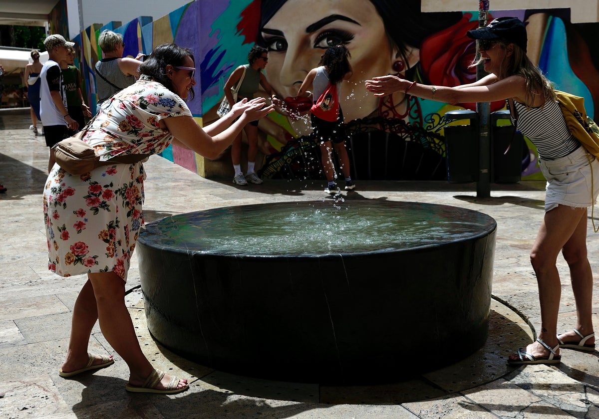 Dos chicas se refrescan en el entorno de calle Granada, en Málaga capital.