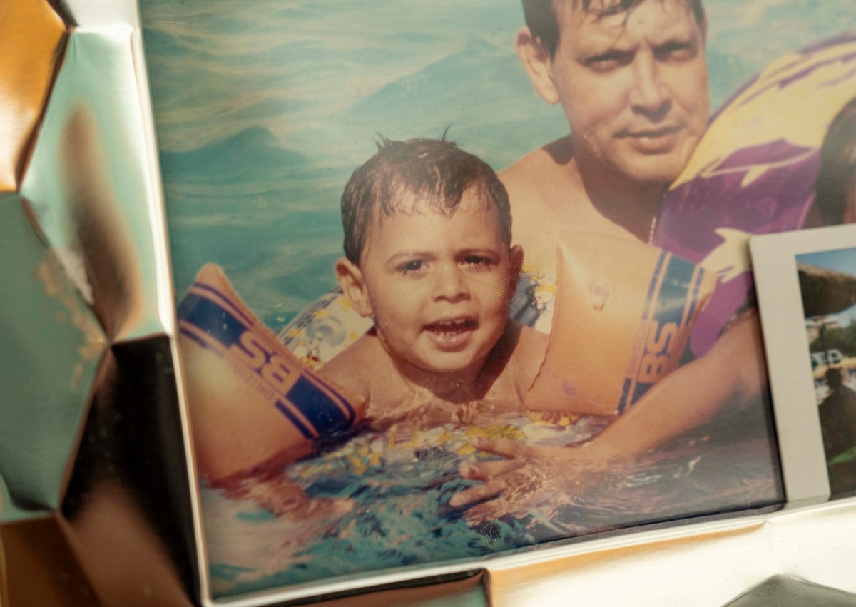 Imagen secundaria 1 - En la imagen superior, Najim muestra una fotocopia del DNI de su hijo; en la fotografía de la izquierda, Mohamed, de pequeño, junto a su padre; a la derecha, las velas que han dejado en su recuerdo en el portal de la víctima.