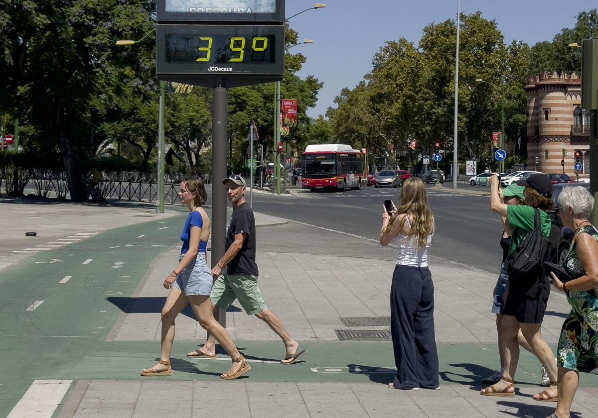 Viandantes en Sevilla junto a un termómetro que marca 39 grados.