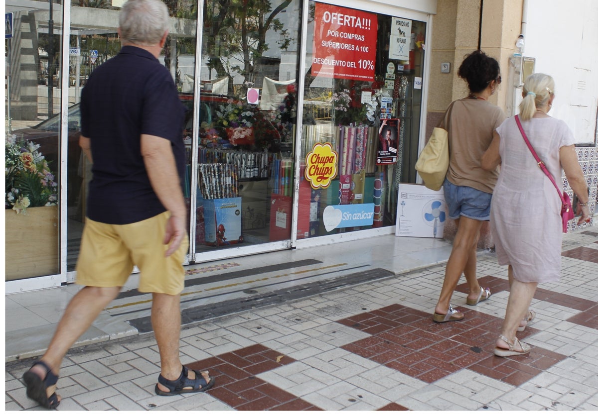 Viandantes pasan frente al escaparate de un comercio en Torremolinos.