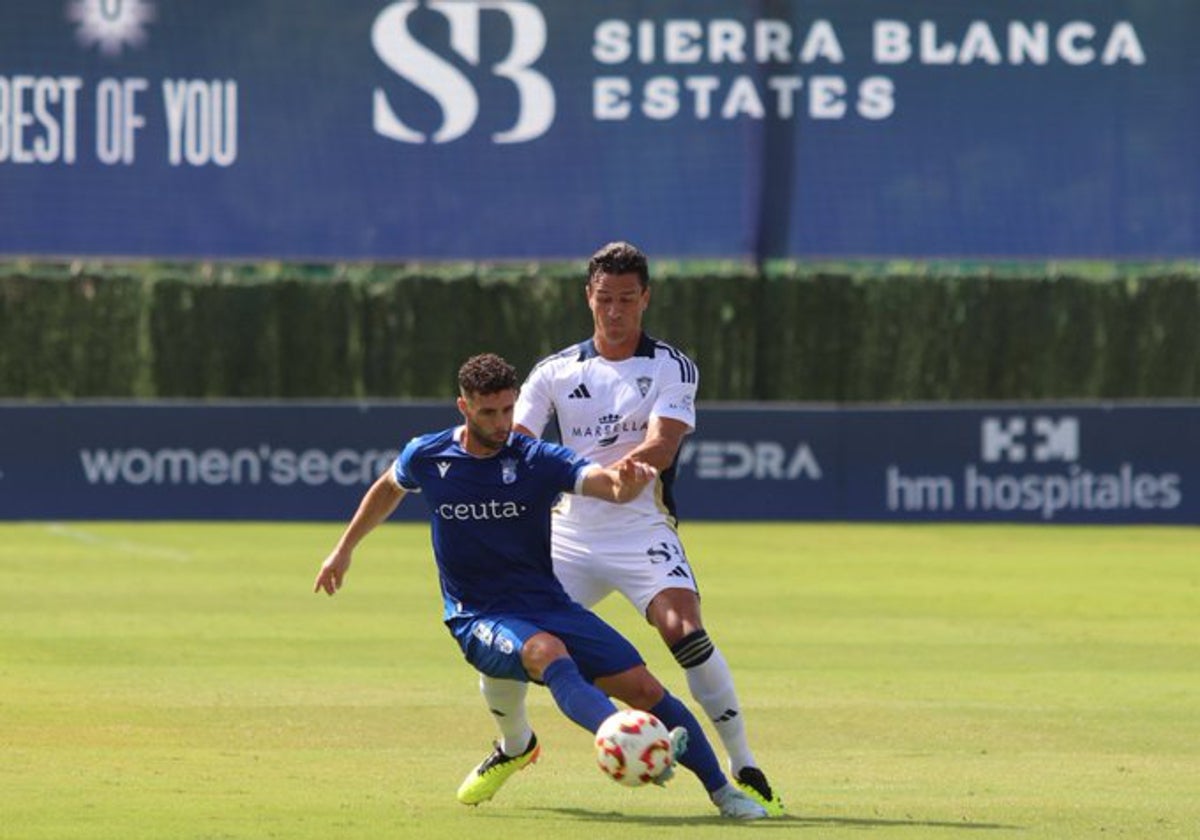 Bernardo, defensa del Marbella, intenta robar el balón a un futbolista del Ceuta.