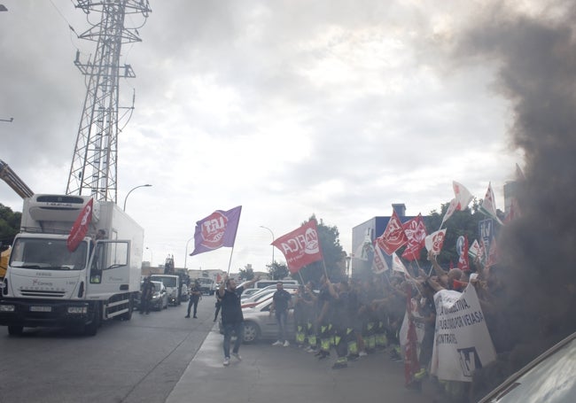 Manifestantes a las puertas de la ITV, entre el humo de una bengala, mientras colocan una bandera sindical en un camión que iba a pasar la inspección.