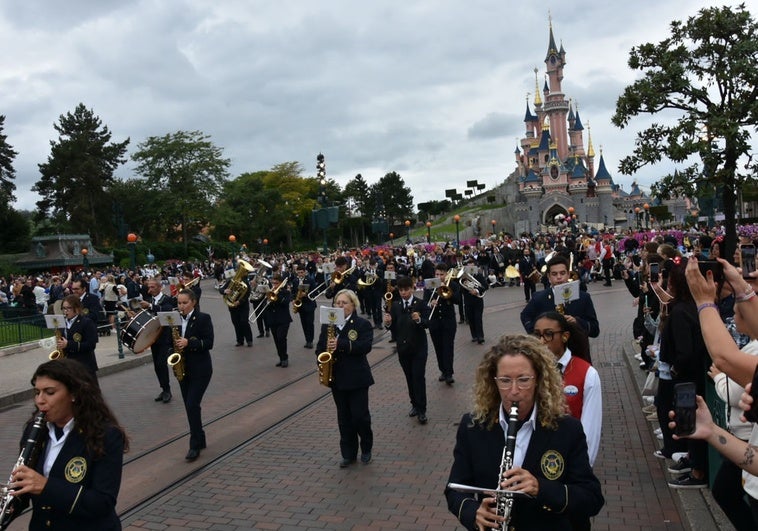 La Banda Municipal de Música de Alhaurín de la Torre desfila con el Castillo de la Bella Durmiendo de Disneyland París al fondo.