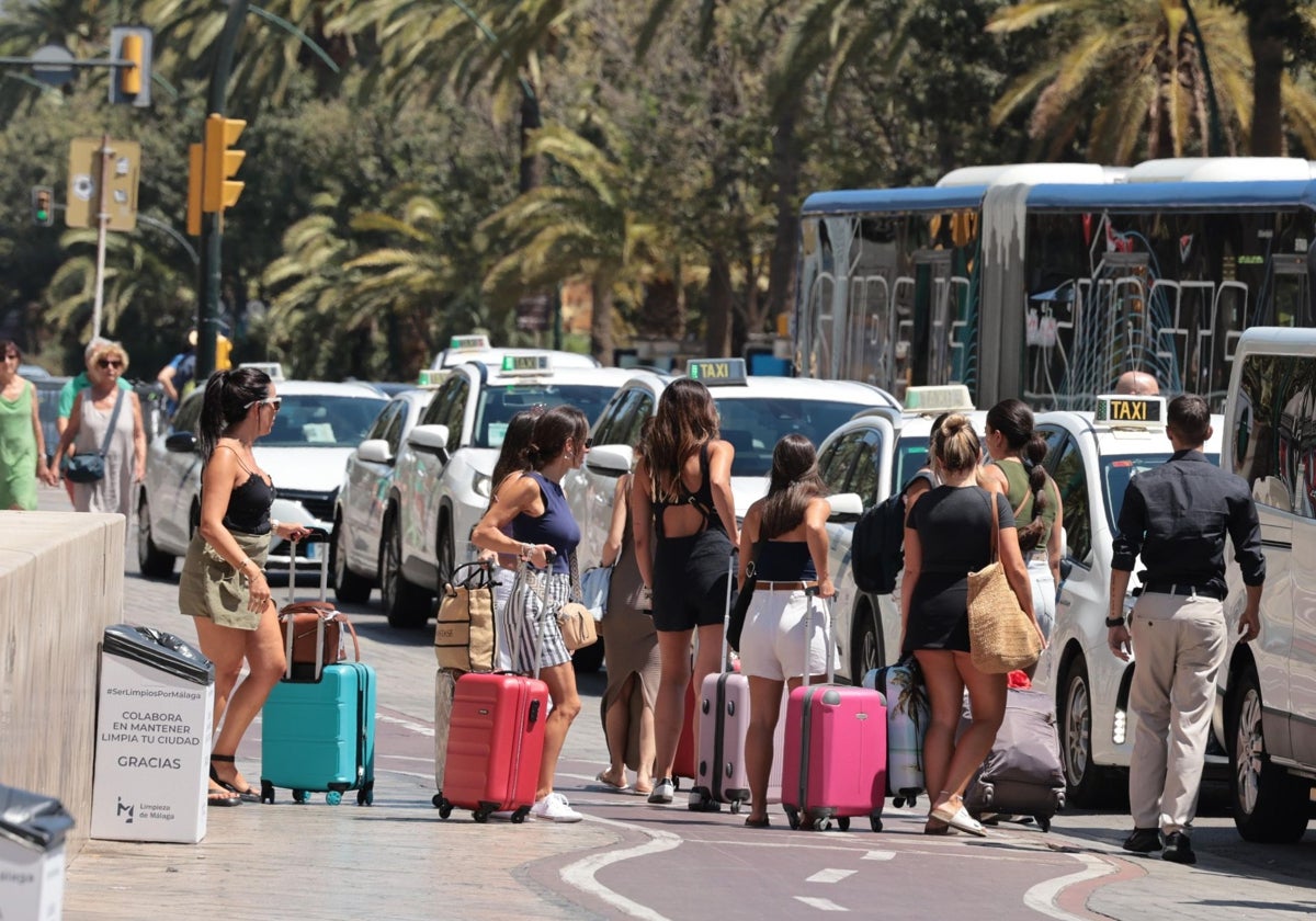 Turistas se dirigen con sus equipajes a una céntrica parada de taxis.