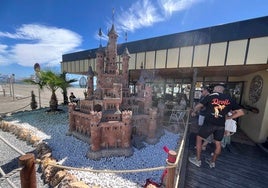 Unos clientes del chiringuito Media Caña observan este viernes el castillo construido por el artista danés en El Peñoncillo.