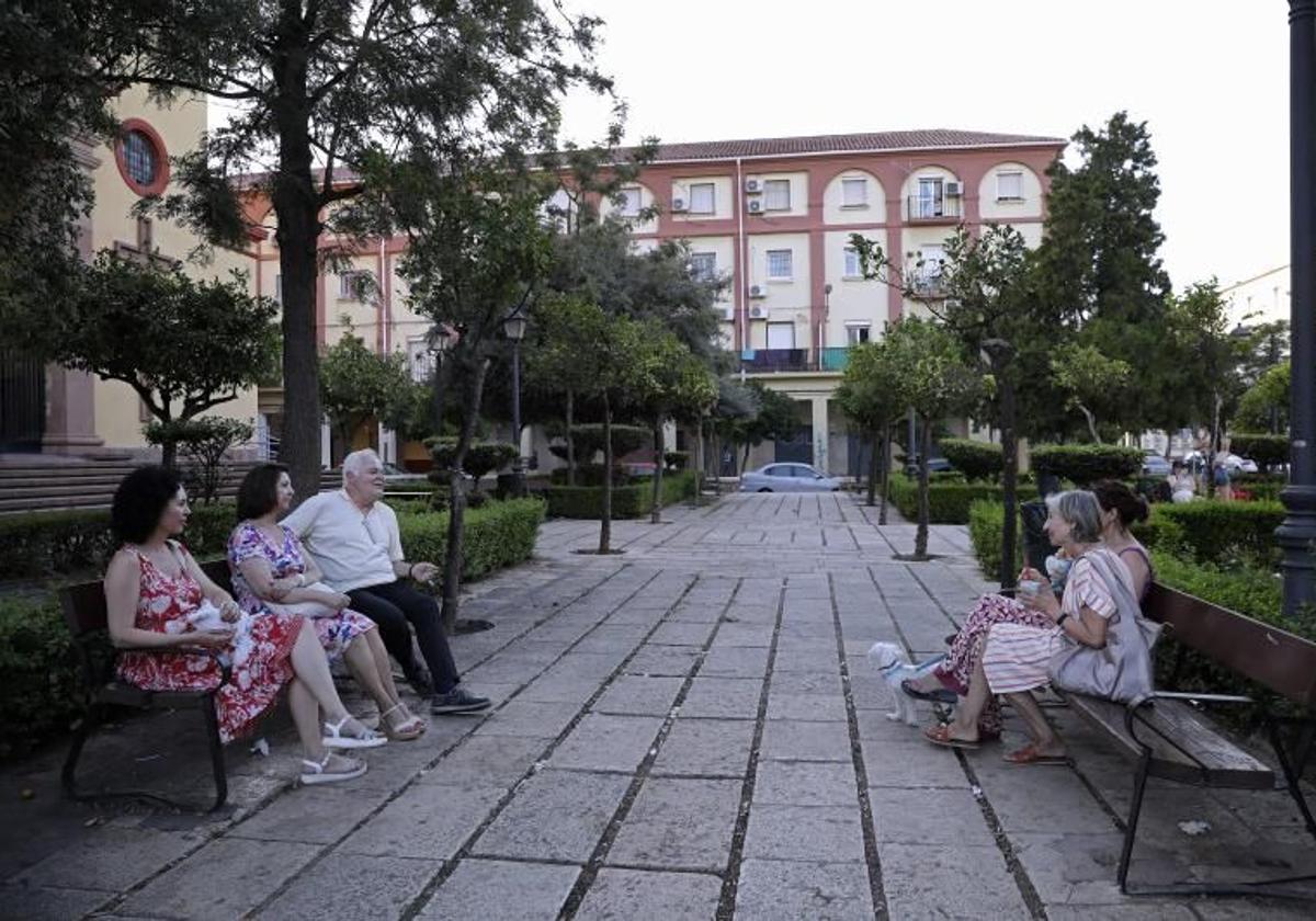 Unos vecinos hablan sentados en unos bancos de una plaza en el barrio de Carranque.