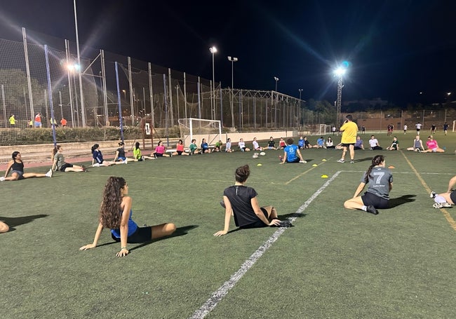 Equipo femenino de rugby de la UMA y los entrenadores realizando el calentamiento antes de comenzar.