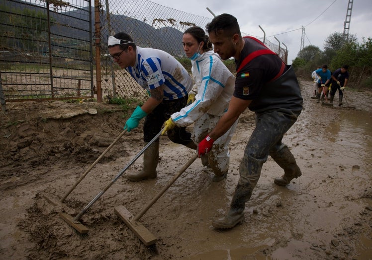 La imagen muestra a un grupo de voluntarios quitando barro en la casa de Cloti