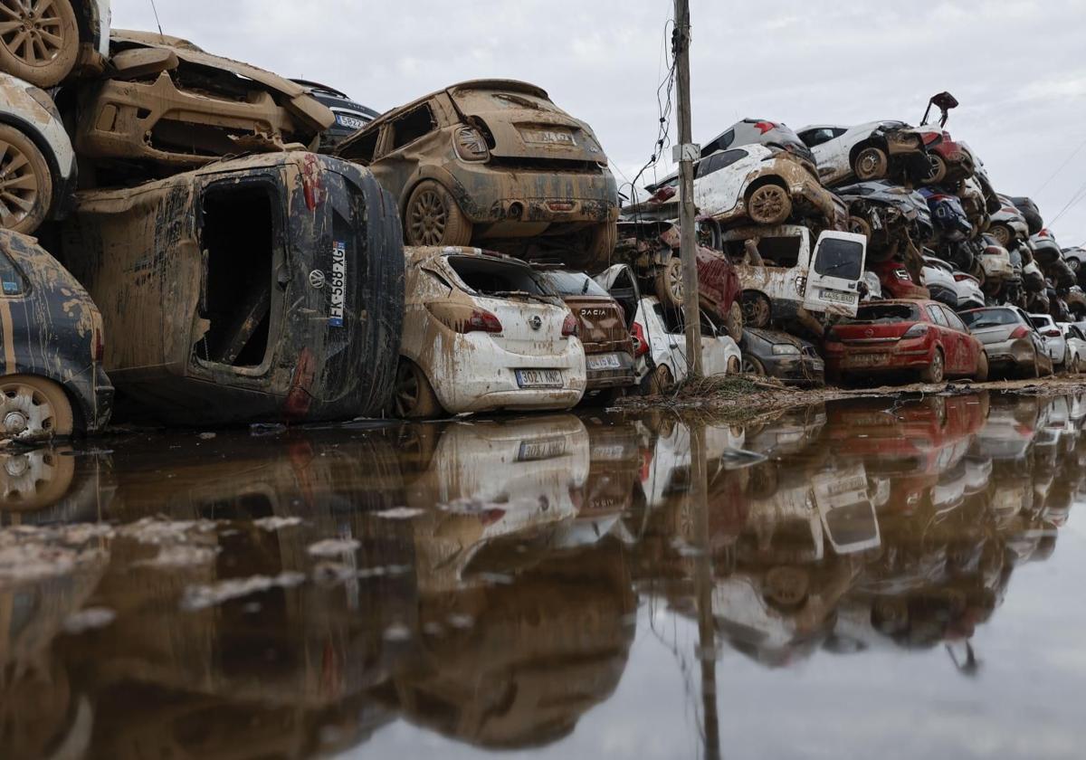 Varios coches, que fueron arrastrados por el agua tras el paso de la dana, almacenados en un descampado en Paiporta.