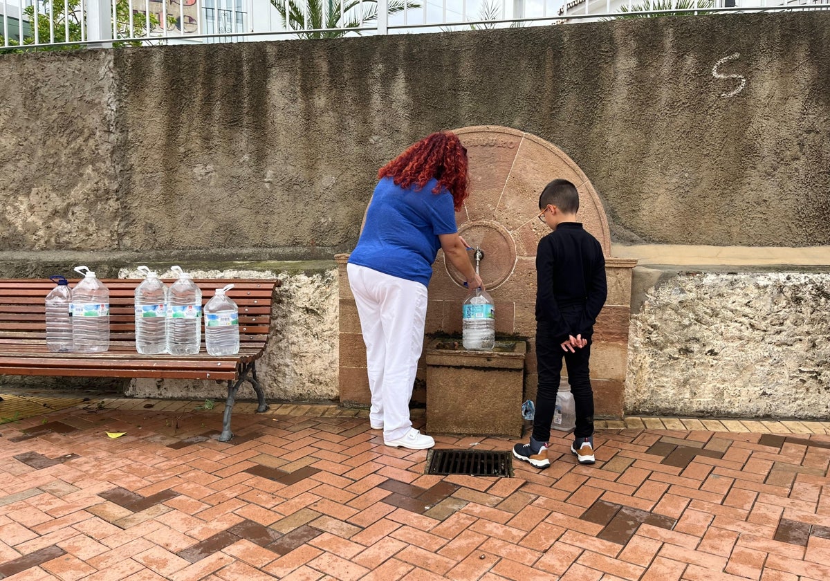 Una mujer y su hijo cogen agua de una de las fuentes de Álora.