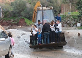 Adultos y niños subidos en la pala de una retroexcavadora, el único medio de transporte viable en algunos diseminados de Almogía.