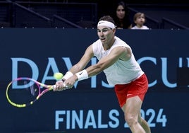 Rafa Nadal, en pleno esfuerzo en el entrenamiento y, al fondo, su esposa, Xisca Perelló, y su hijo Rafael siguiéndole.