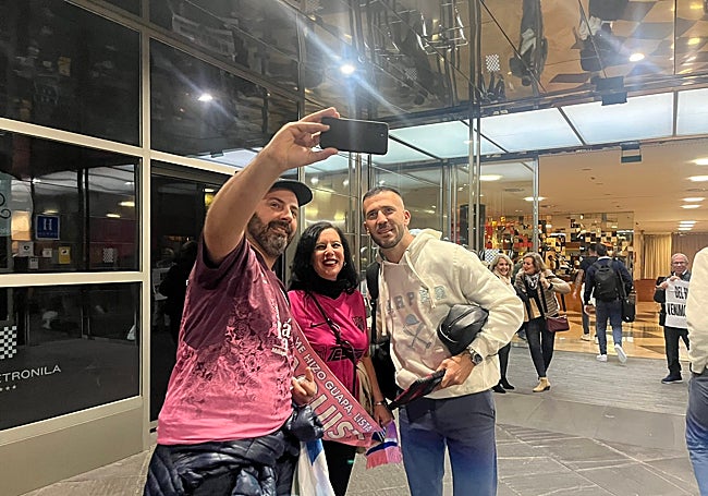 Dioni, delantero del Málaga, se para para hacerse una foto con dos aficionados malaguistas.