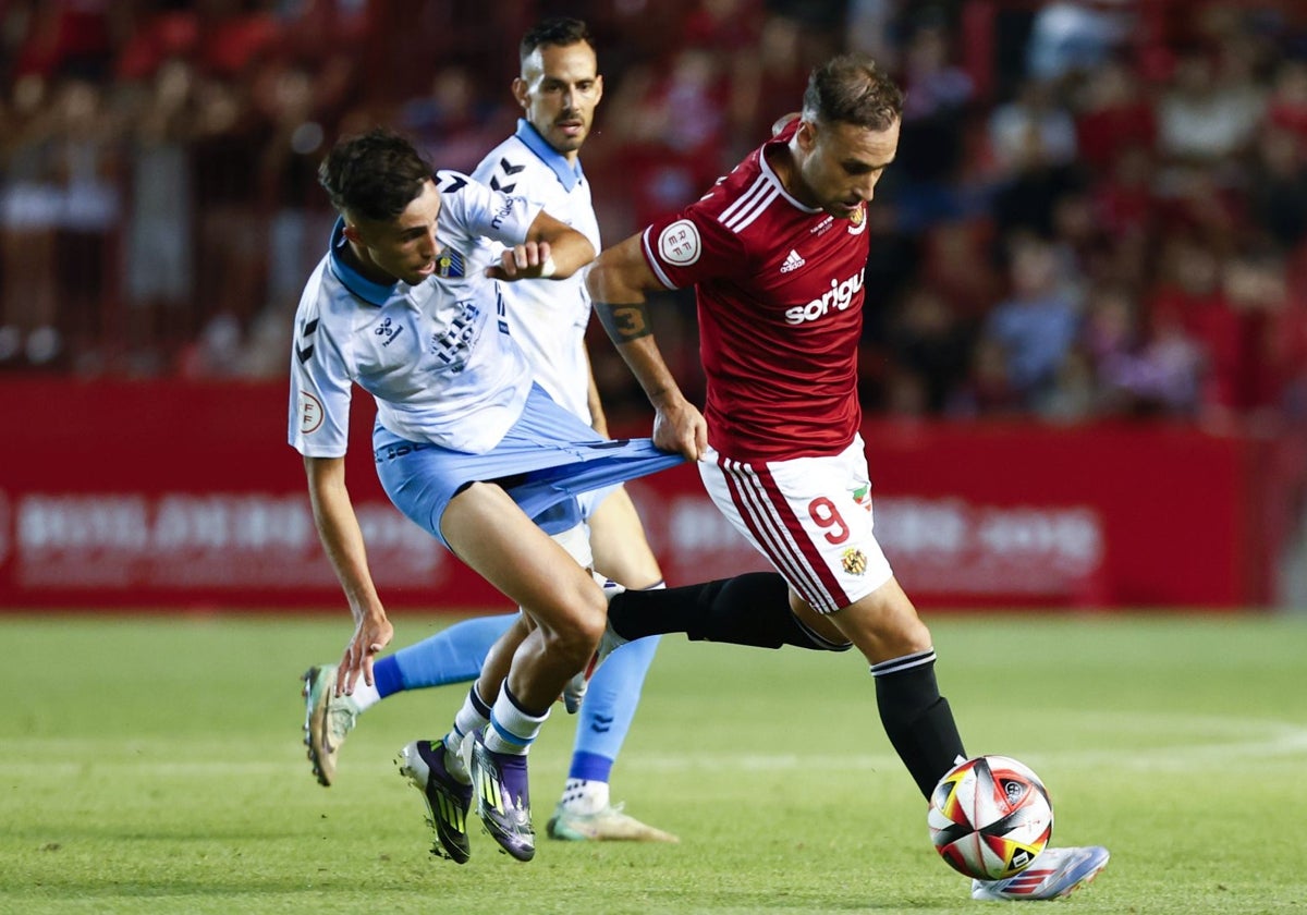 Larrubia intenta hacerse con el balón mientras es agarrado en el partido de Tarragona.