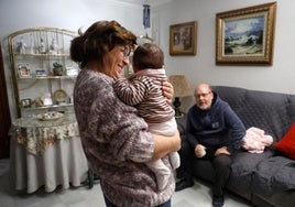 Ángeles y Jesús, en el salón de su casa, con la pequeña que tienen acogida.