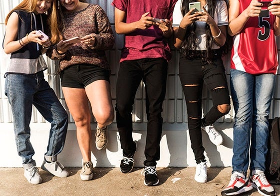 Un grupo de jóvenes usan su teléfono en una reunión social.