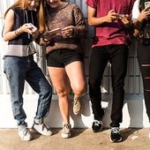 Un grupo de jóvenes usando su teléfono en una reunión social.