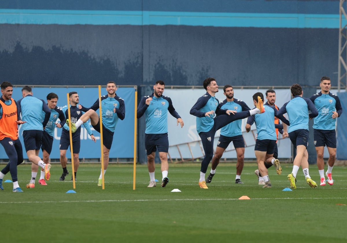 Los jugadores del Málaga se entrenan bajo la lluvia en la sesión del martes.