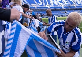 Dely Valdés, al fondo, y Darío Silva, vestidos con la nueva camiseta 'vintage', firman autógrafos a los niños que acudieron al entrenamiento de puertas abiertas del martes.