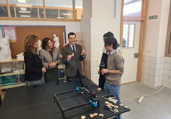 El presidente de la Junta muestra las insignias elaboradas por los alumnos en el taller del centro.