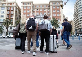 Turistas con maletas en dirección al alojamiento elegido en la ciudad.