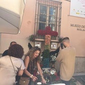 Un hombre fotografía la cruz adornada con flores en la plaza de Viñeros.