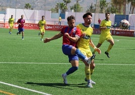 'Gato', jugador del Torre del Mar, golpea el balón incomodado por un jugador del Huétor Tájar.