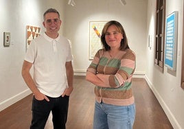 Ester Ramos y Sergio Croma pasan junto a la exposición.