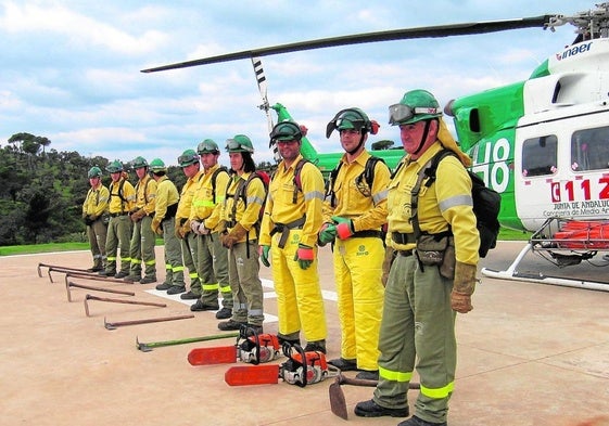 Operativos del Plan Infoca, delante de un helicóptero utilizado para la extinción.