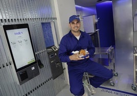 Ricardo Álvarez, junto a la pantalla de pedidos, con una de sus hamburguesas.