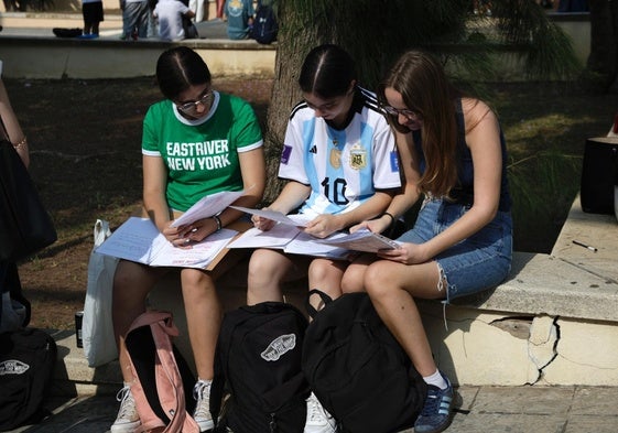 Tres jóvenes repasan antes de hacer uno de los exámenes de la selectividad, en Málaga.