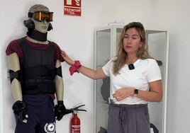 Marina Soler, trabajadora social del proyecto, junto al traje del programa Vivir en Casa.