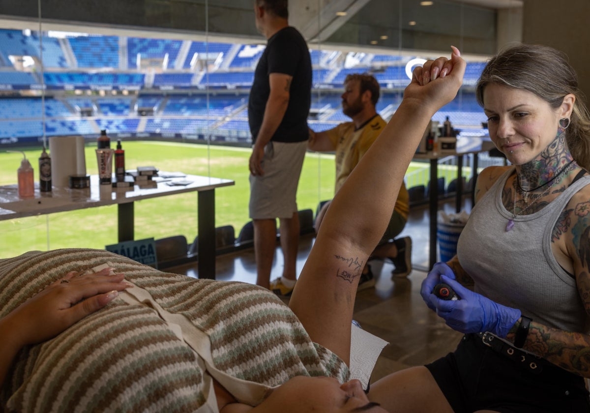 Una aficionada se mira el tatuaje que le ha hecho Erica.