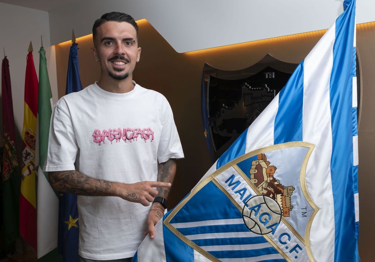 Joaquín posa junto a la bandera del Málaga tras firmar su nuevo contrato.