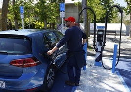 Un conductor recarga su vehículos eléctrico.