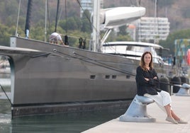 Sasha Romashova, sentada junto a un gran velero en la marina de megayates de Málaga.
