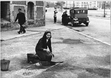 Mujer cogiendo agua de un registro en El Perchel.