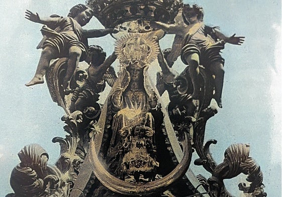 La Virgen de la Victoria, en una foto coloreada, vestida con ropajes y presidiendo su antiguo templete.
